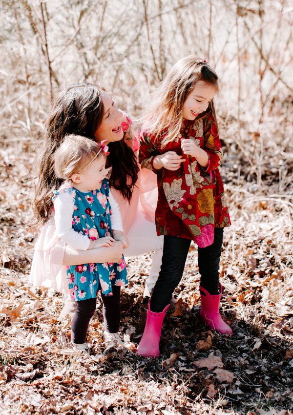 Woman laughing with two young girls wearing spring outfits