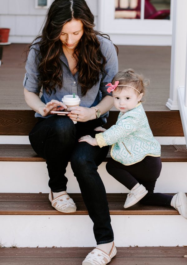 Woman holding coffee and cell phone and child
