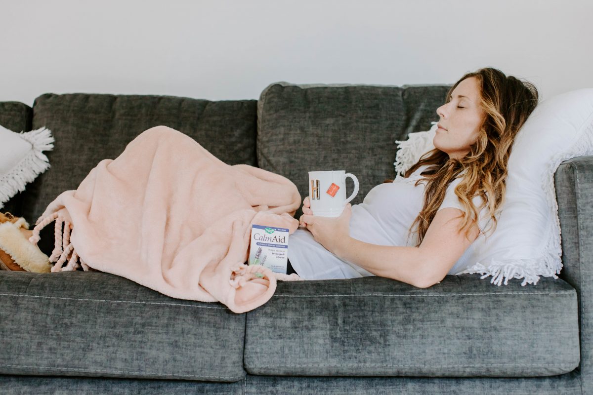 PMS Woman Laying on the Couch with Coffee Mug and Vitamins