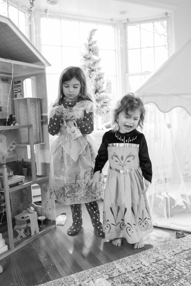 Black and white photo of two little girls standing side by side in princess dresses