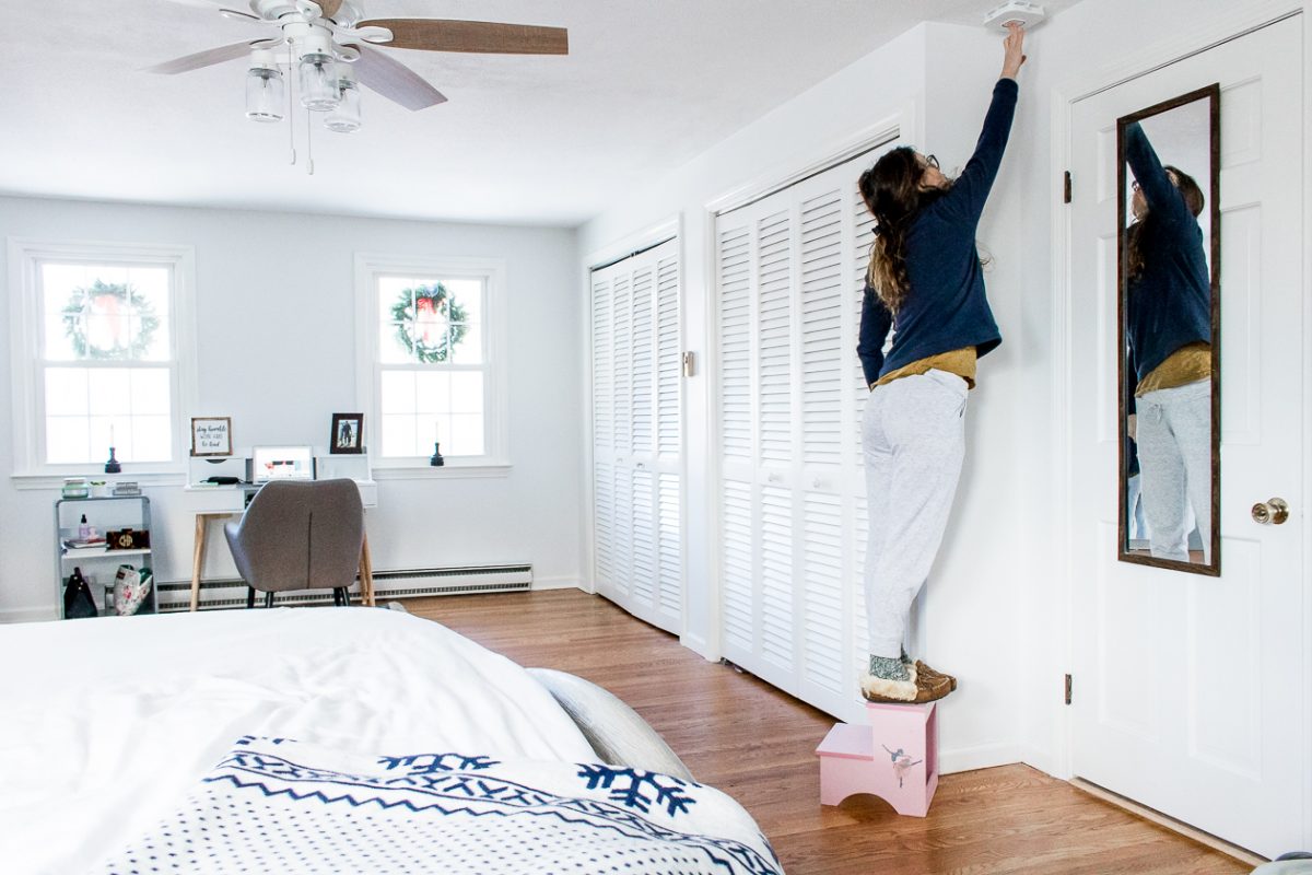 Woman Installing Fire Alarm on Ceiling in Bedroom - How to Keep Your Family Safe with Onelink Smart Smoke & Carbon Monoxide Alarm