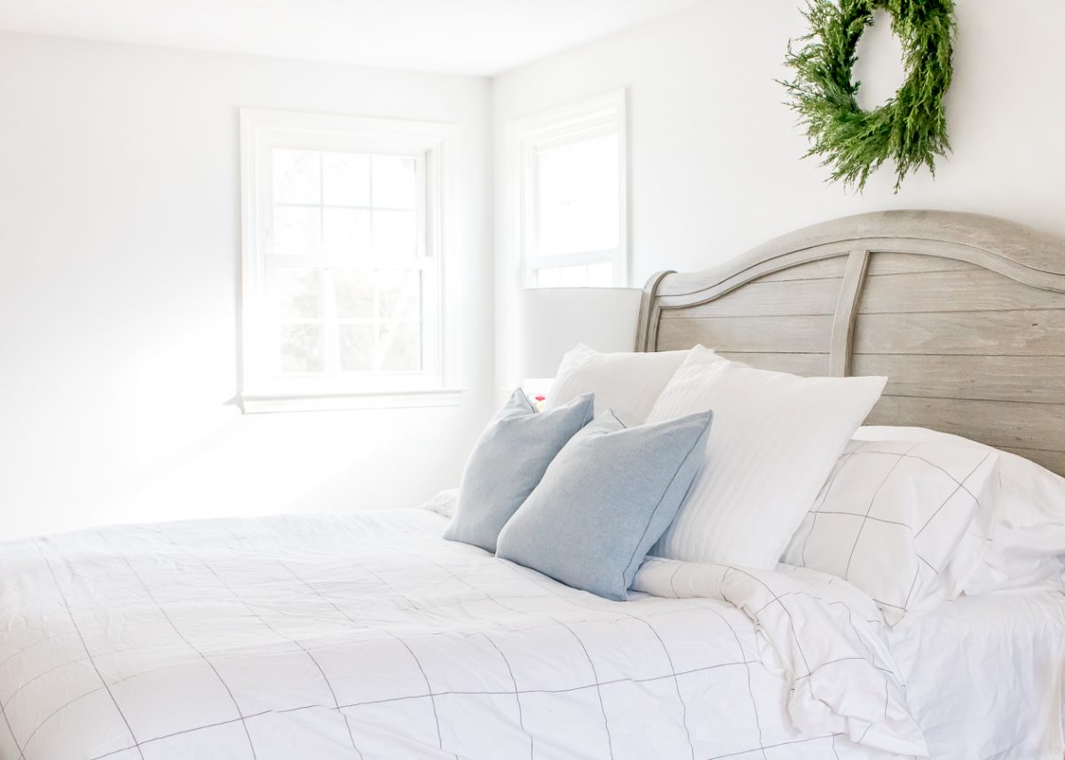 Bright White Bedroom with Gray Headboard and Green Boxwood Wreath on the Wall above the Bed