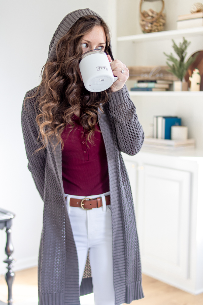 girl wearing hooded sweater and sipping coffee