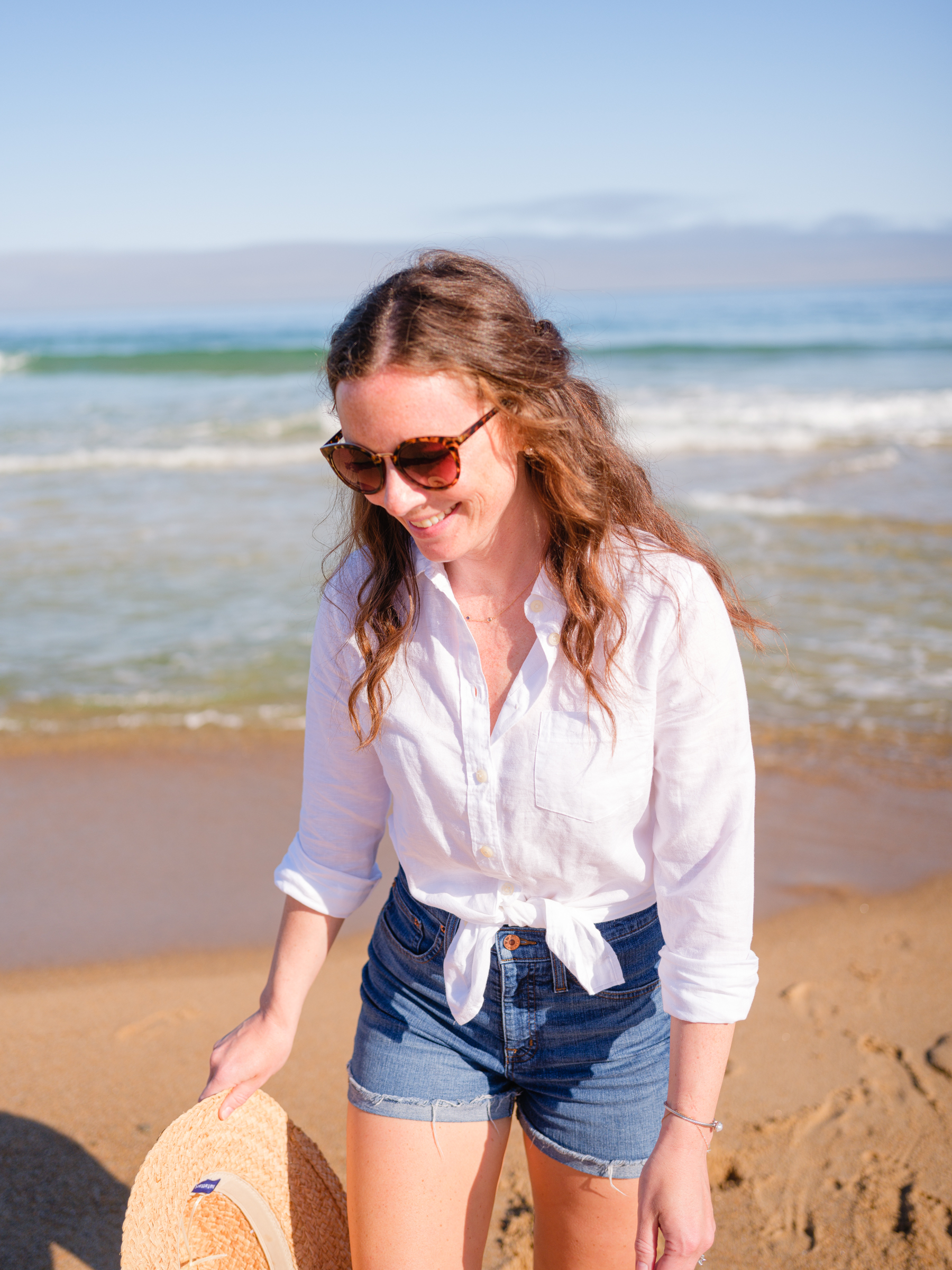 woman at beach with summer hat and white linen button up
