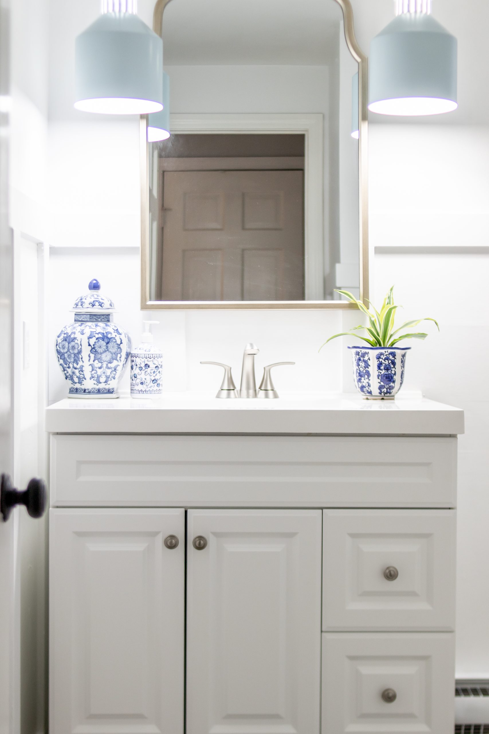 Cape Cod inspired bathroom light blue pendant lights arch mirror white vanity blue ginger jar decor