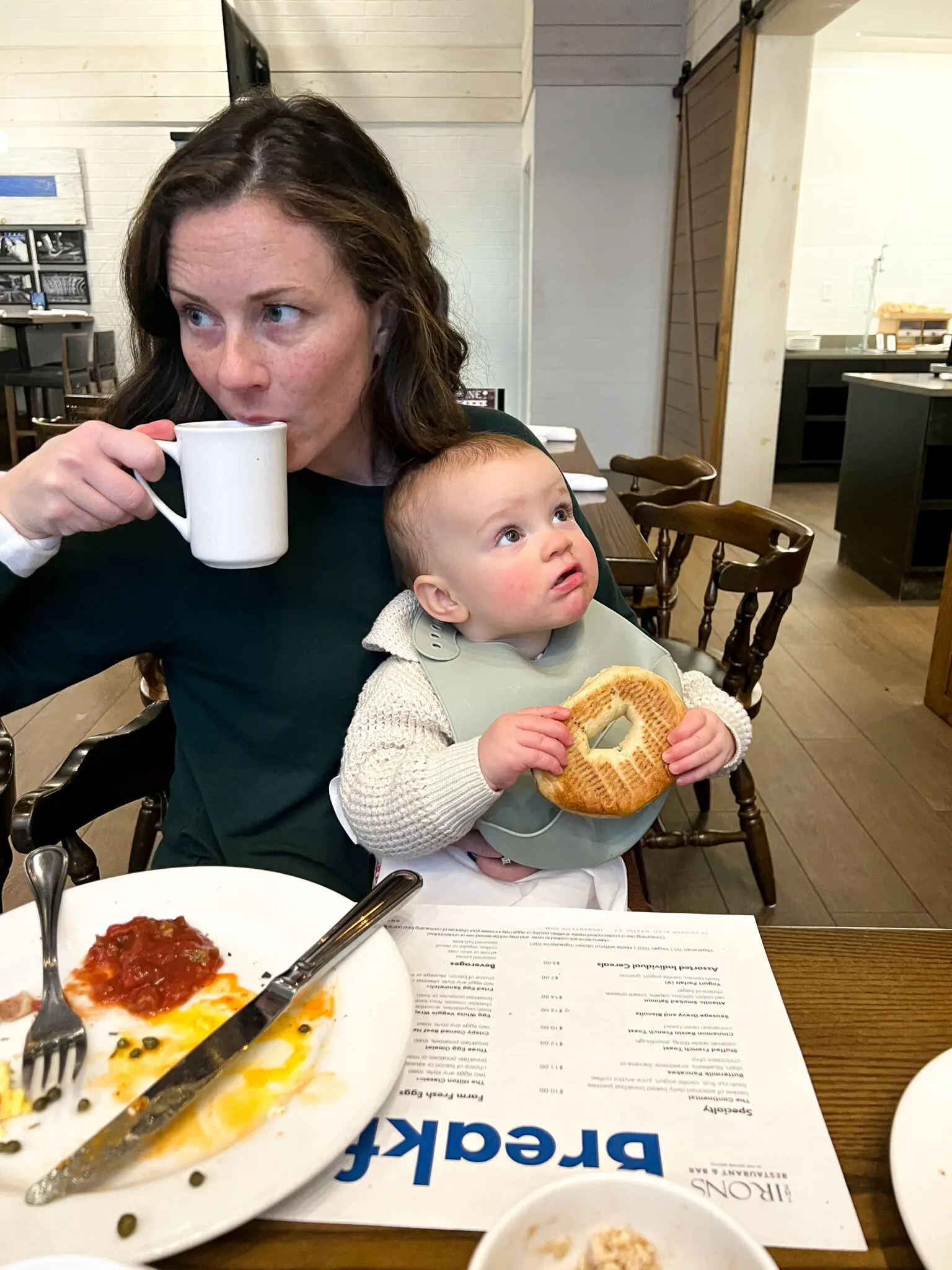 Mom sipping coffee while holding baby with bagel at Irons Hilton Mystic
