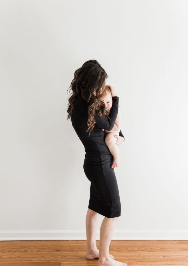 Mom in black dress holding baby in diaper 15 months old