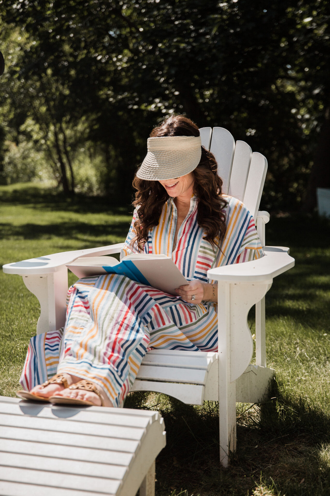 Woman reading book outside in striped dress