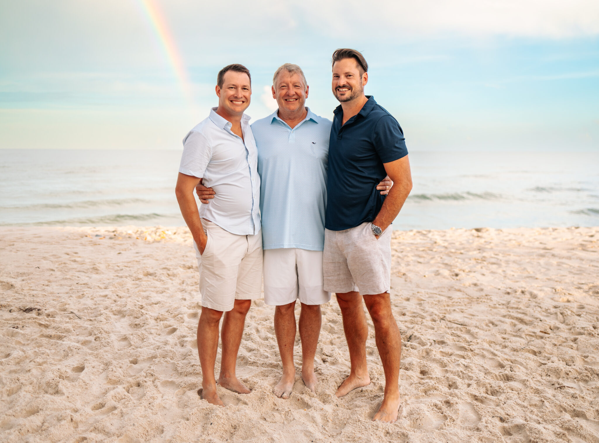 Dad and adult sons in blue and tan family photo at the beach